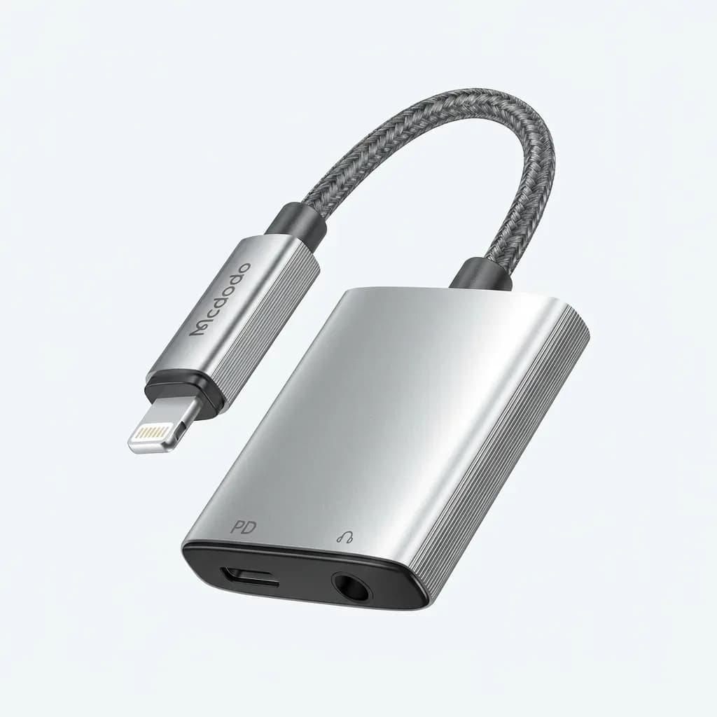 Mcdodo 2-in-1 Lightning audio adapter in silver with a braided cable, Lightning male connector, 3.5mm headphone jack and Lightning charging port on a white background.
